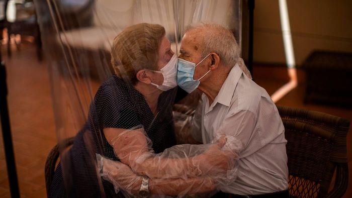 Agustina Ca&ntilde;amero, 81, dan Pascual P&eacute;rez, 84, berpelukan dan berciuman melalui selembar plastik untuk mencegah penyebaran virus corona COVID-19 di panti jompo di Barcelona, Spanyol, Senin, 22 Juni 2020.
