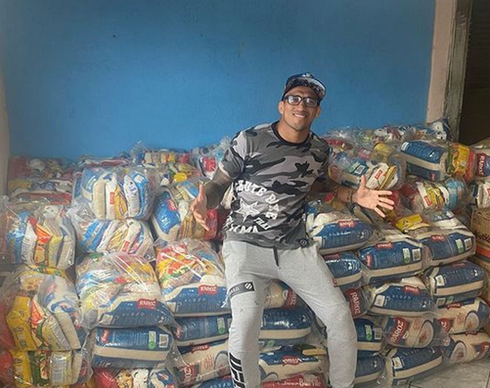 Jagoan UFC, Charles Oliveira bersama beberapa bungkus makanan yang ia donasikan.