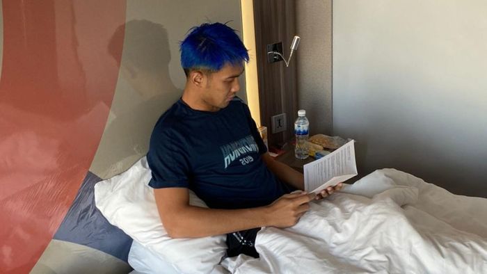 Pemain ganda putra Indonesia, Fajar Alfian, membaca buku selama masa karantina di Bangkok, Thailand.