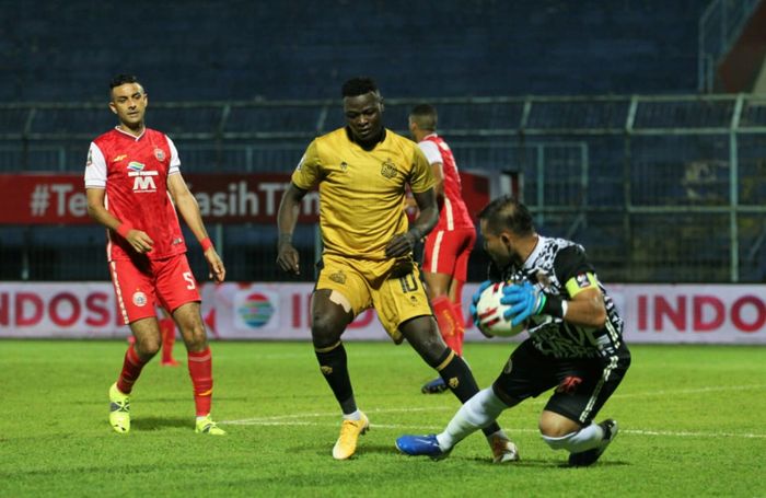 Pemain Bhayangkara Solo FC, Ezechiel N'douassel, berebut bola dengan kiper Persija, Andritany Ardhiyasa dalam laga di Stadion Kanjuruhan, Malang, Rabu (31/3/2021).
