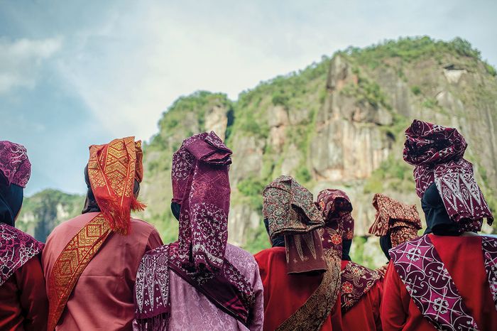 Several women in traditional dress are watching one of the performances of the Pasa Harau Art & Culture Festival in the Harau Valley.