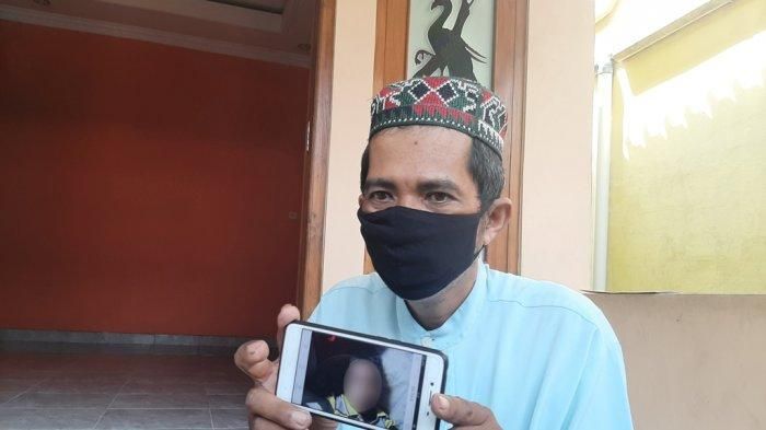 Bandiman memperlihatkan foto anaknya yang meninggal usai menyantap paket sate misterius, Senin (26/4/2021)