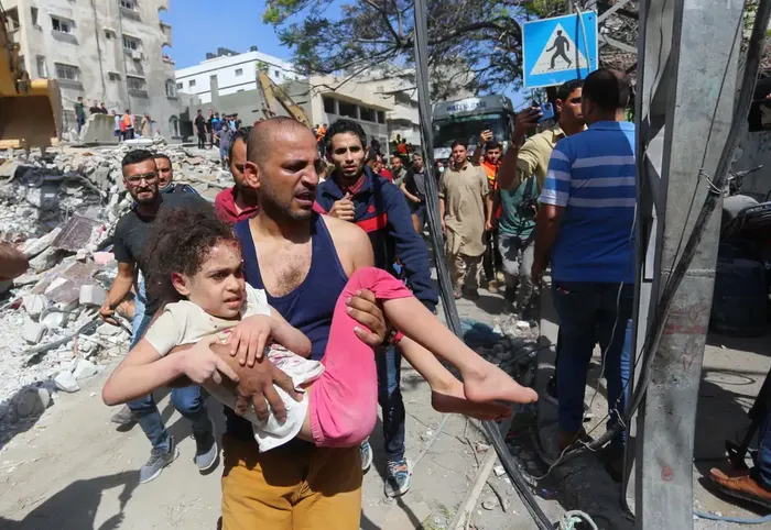 Warga Palestina menyelamatkan Suzy Eshkuntana yang berusia 6 tahun dari puing-puing rumahnya setelah serangan udara oleh tentara Israel di lingkungan al-Rimal Kota Gaza, Gaza, pada 16 Mei 2021.