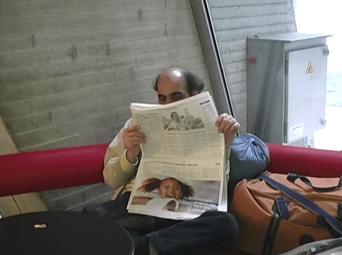 Mehran Karimi membaca koran di bandara