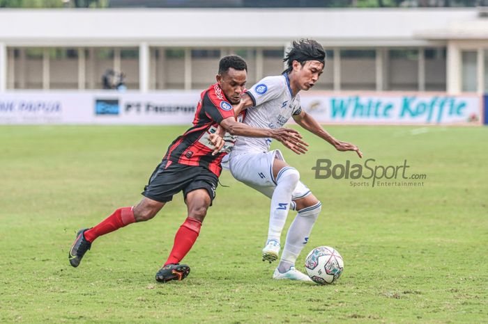 Bek sayap kiri Arema FC, Johan Alfarizi (kanan), sedang menguasai bola dan dibayangi pemain Persipura Jayapura, Gunansar Mandowen (kiri), dalam laga pekan kelima Liga 1 2021 di Stadion Madya, Senayan, Jakarta, 29 September 2021.
