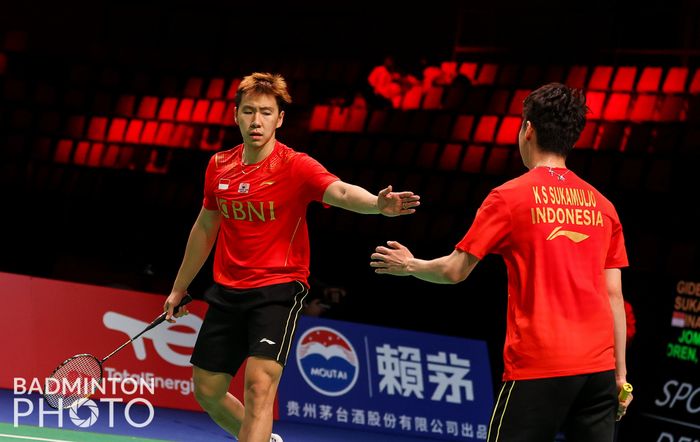 Pasangan ganda putra Indonesia, Marcus Fernaldi Gideon/Kevin Sanjaya Sukamuljo, melakukan tos di sela pertandingan melawan wakil Thailand, Supak Jomkoh/Kittinupong Kedren, pada lanjutan penyisihan Grup A Thomas Cup 2020 di Ceres Arena, Aarhus, Denmark, Senin (11/10/2021).