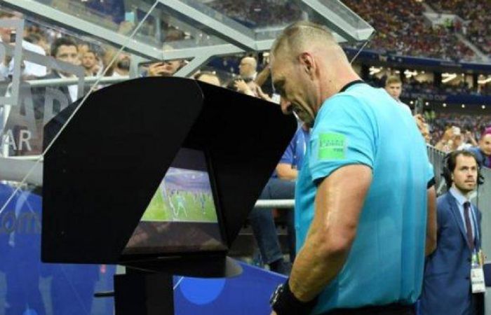 Wasit sedang mengamati kembali rekaman adegan pertandingan melalui video assistant referee (VAR).