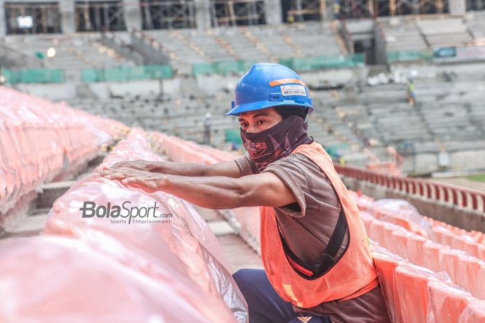 Seorang pekerja sedang menata kursi Jakarta Internasional Stadium, Papanggo, Jakarta Utara, 7 Desember 2021.