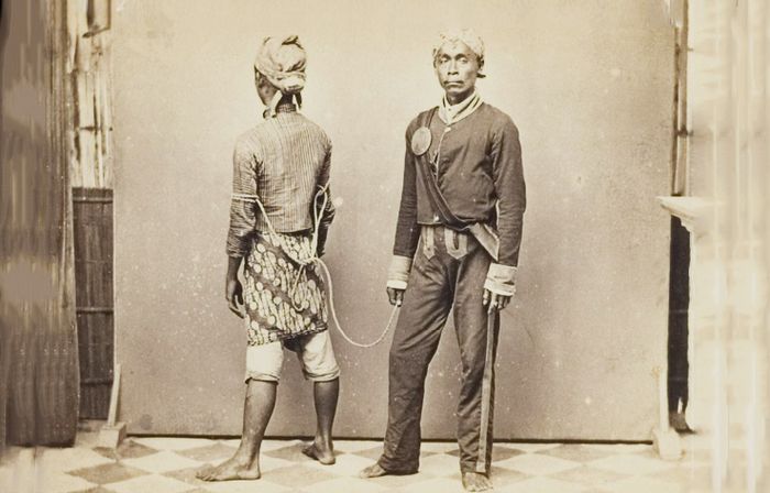 Potret polisi Hindia-Belanda yang telah berhasil menangkap seorang kecu di Jawa sekitar tahun 1870.