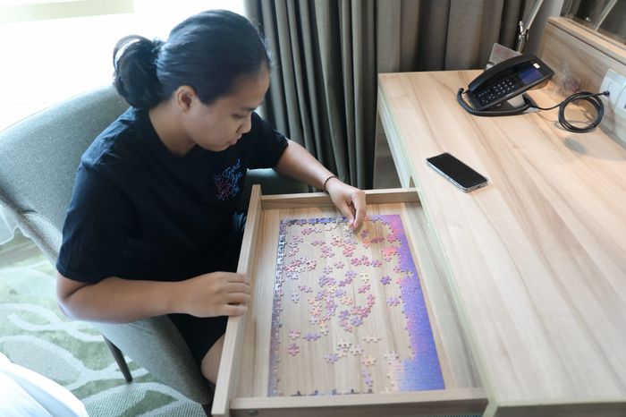Pemain ganda putri Indonesia, Jesita Putri Miantoro, sedang bermain puzzle untuk mengusir kejenuhan.