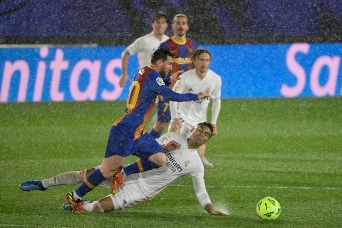 Lionel Messi (atas) berebut bola dengan Casemiro dalam partai El Clasico Real Madrid vs Barcelona di Valdebebas (10/4/2021).