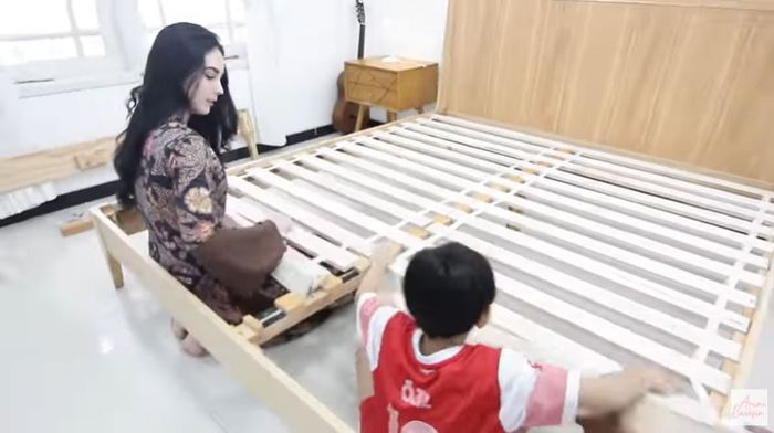 Arumi Bachsin pasang kerangka ranjangnya dibantu sang putra