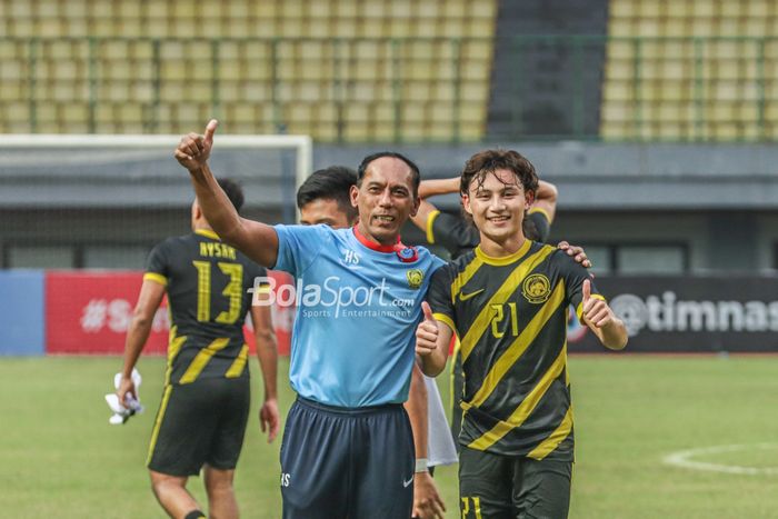 Pelatih timnas U-19 Malaysia, Hassan Sazali Mohd Waras (kiri), sedang berfoto bersama dengan pemainnya bernama Muhammad Haiqal Haqeemi Hairi (kanan) di Stadion Patriot Candrabhaga, Bekasi, Jawa Barat, 13 Juli 2022.