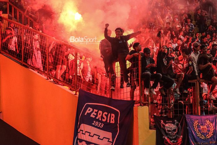 Suporter Persib Bandung (pendukung Persib Bandung) sedang menyalakan flare atau kembang api atau suar atau petasan seusai laga di Stadion Wibawa Mukti, Cikarang, Jawa Barat, 24 Juli 2022.