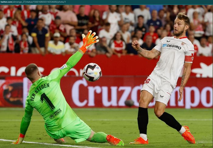 Aksi kiper Barcelona, Marc-Andre ter Stegen, mencegat bola dari gelandang Sevilla yang juga eks rekannya, Ivan Rakitic di Stadion Ramon Sanchez Pizjuan, Minggu (4/9/2022) dini hari WIB.