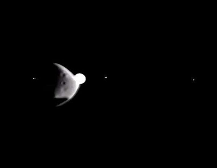 Tangkapan layar video dari kamera Mars Express ESA yang menunjukkan momen Deimos akan melintasi planet Jupiter sebagai titik terang yang besar.
