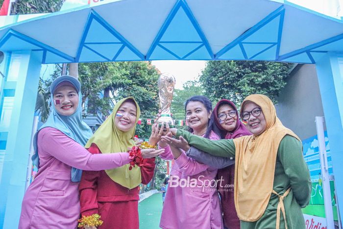 Sejumlah ibu-ibu sedang memegang trofi tiruan Piala Dunia 2022 Qatar di Kampung Piala Dunia 2022 Qatar di Indonesia yang terletak pada Komplek Maharaja Depok Cluster Cemara, Jawa Barat, 21 November 2022.