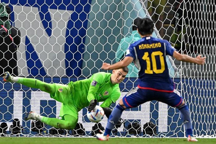 Kiper timnas Kroasia, Dominik Livakovic, mengeblok tendangan penalti Takumi Minamino dalam duel Piala Dunia 2022 di Al Janoub Stadium (5/12/2022).