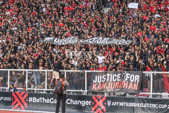 Suporter timnas Indonesia membentangkan spanduk terkait tragedi Kanjuruhan dalam laga pekan pertama Grup A Piala AFF 2022 di Stadion Gelora Bung Karno, Senayan, Jakarta, 23 Desember 2022.