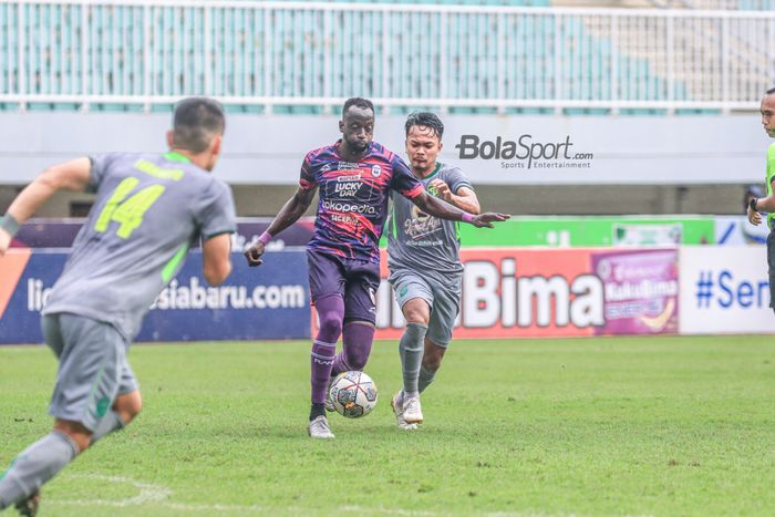 Gelandang asing RANS Nusantara FC, Makan Konate (kiri), sedang menguasai bola dan dibayangi pemain Persebaya Surabaya bernama Muhammad Hidayat (kanan) dalam laga pekan ke-27 Liga 1 2022 di Stadion Pakansari, Bogor, Jawa Barat, Selasa (28/2/2023).