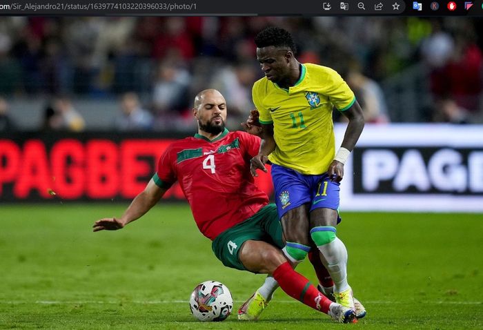 Sofyan Amrabat (merah) berebut bola dengan Vinicius Junior (kuning) dalam laga uji coba antara timnas Maroko dan timnas Brasil di Grand Stade de Tanger, Sabtu (25/3/2023).