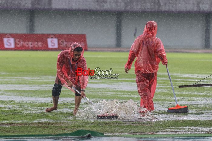Sejumlah petugas sedang membereskan genangan air yang menggenang seusai Laga pekan ke-22 Liga 1 2023 antara Dewa United versus Bali United sempat terpaksa ditunda sementara karena cuaca hujan dan petir di Stadion Indomilk Arena, Tangerang, Banten, Jumat (8/12/2023).