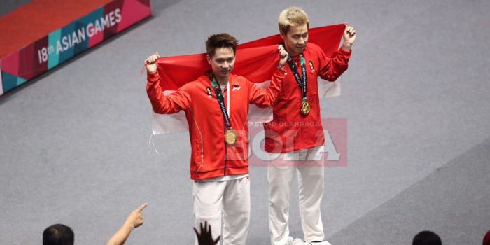    Marcus Fernaldi Gideon (kanan) dan Kevin Sanjaya Sukamuljo (kiri) membentangkan bendera Merah Putih seusai menjuarai nomor ganda putra pada Asian Games 2018.