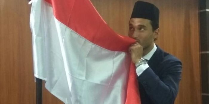    Pose pemain naturalisasi Indonesia, Ezra Walian, saat mencium bendera merah putih selepas disumpa