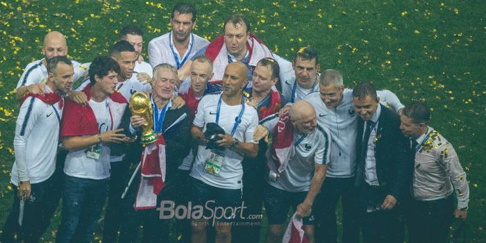 Pelatih Prancis, Didier Deschamps, memegang trofi juara Piala Dunia 2018 didampingi stafnya.