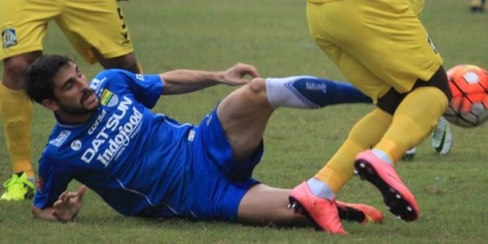 Gelandang Persib, Robertino Pugliara terjatuh di antara dua pemain Persiba Balikpapan di Stadion Wib