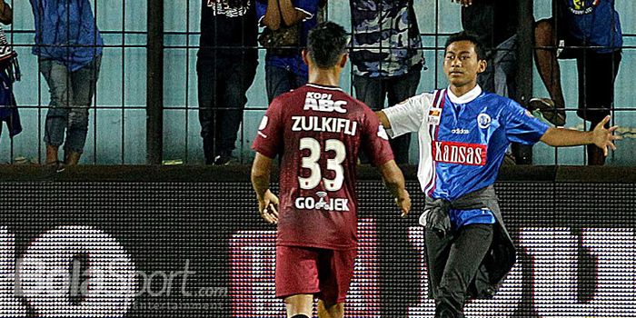 Bek PSM Makassar, Zulkifly Syukur, menerima sambutan seorang anggota pendukung Arema FC, Aremania, s