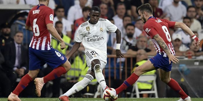 Penyerang Real Madrid, Vinicius Junior, berusaha melewati hadangan dua pemain Atletico Madrid pada p