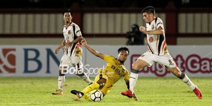 Pemain Bhayangkara FC, Muhammad Hargianto, melepas  tackle ke pemain Mitra Kukar, Fernando Rodriguez