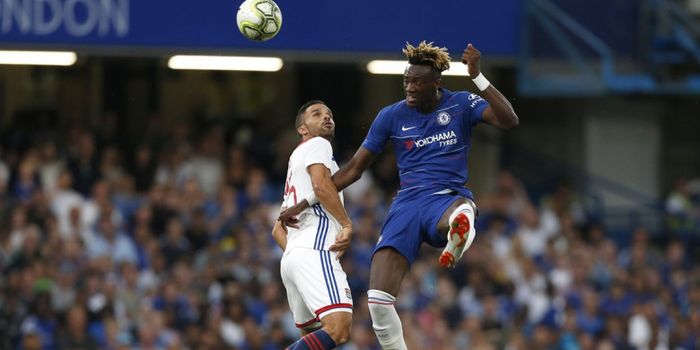 Penyerang Chelsea, Tammy Abraham, berebut bola melawan pemain bertahan Olympique Lyon pada laga Inte