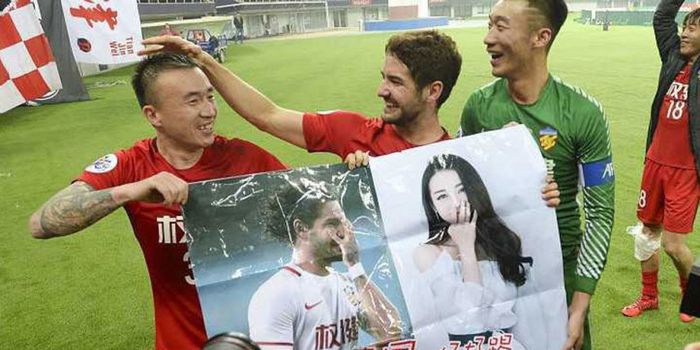 Pemain Tianjin Quanjian, Alexandre Pato (tengah) bersama dua rekan setimnya memegang poster yang berisi foto dirinya bersama artis China, Dilraba Dilmurat, yang diberikan fans, setelah menang 4-1 atas Jeonbuk Motors di Liga Champions Asia, Rabu (14/3/2018)