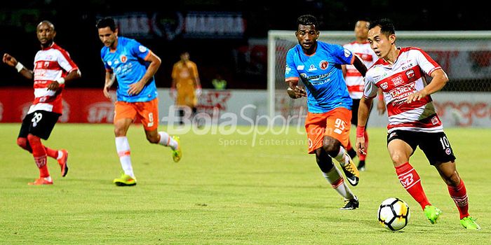 Gelandang Madura United, Slamet Nurcahyono, berupaya melewati hadangan pemain belakang Perseru Serui