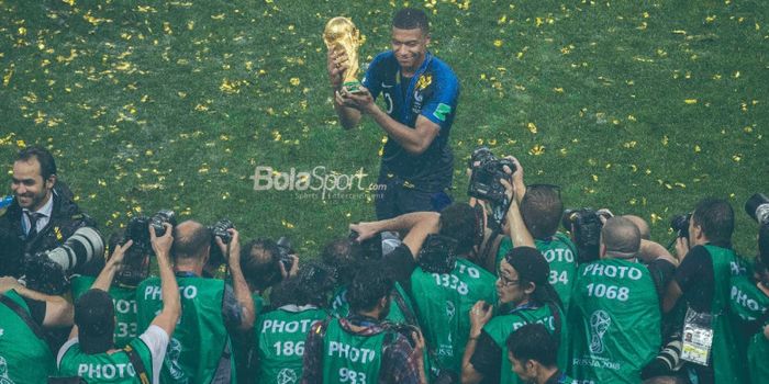 Penyerang Prancis, Kylian Mbappe, berpose dengan trofi juara Piala Dunia 2018.
