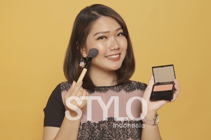wanita mengaplikasikan blush on dengan warna sesuai kulit