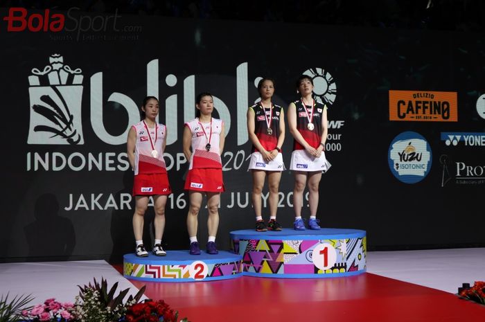 Pasangan ganda putri Jepang, Yuki Fukushima/Sayaka Hirota (kanan, jersey hitam) berpose di podium juara bersama Misaki Matsutomo/Ayaka Takahashi (kiri) seusai final Indonesia Open 2019 di Istora Senayan, Jakarta, Minggu (21/7/2019).