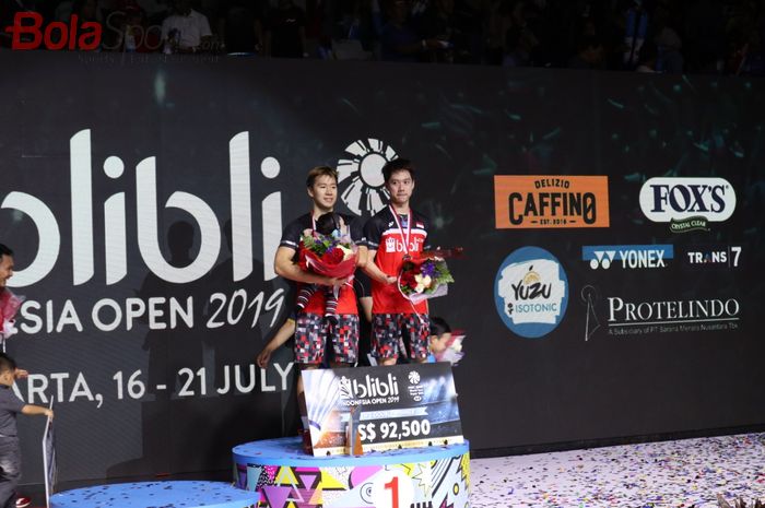 Pasangan ganda putra Indonesia, Marcus Fernaldi Gideon/Kevin Sanjaya Sukamuljo, berpose di podium juara Indonesia Open 2019 di Istora Senayan, Jakarta, Minggu (21/7/2019)