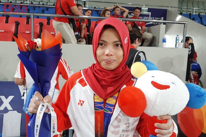Lifter putri Indonesia, Lisa Setiawati, berpose dengan medali setelah tampil di kelas 45 kg SEA Games 2019, di Aquino Stadium, Manila, Minggu (1/12/2019).