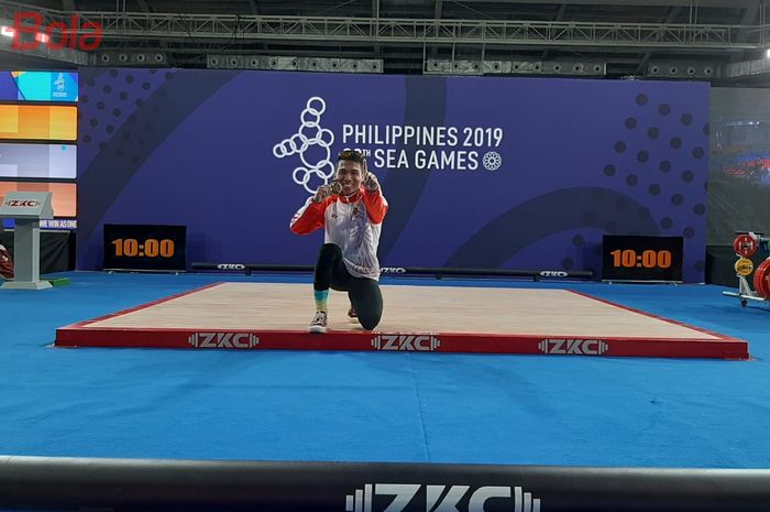 Lifter putra Indonesia, Deni, berpose dengan medali emas dari kelas 67 kg SEA Games 2019 di Ninoy Aquino Stadium, Selasa (3/12/2019).