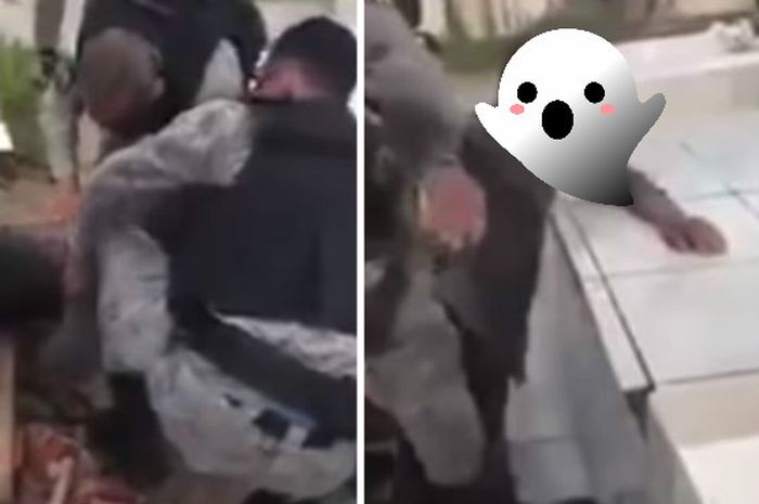 Petugas polisi mengeluarkan seorang pria dari dalam sebuah makam.