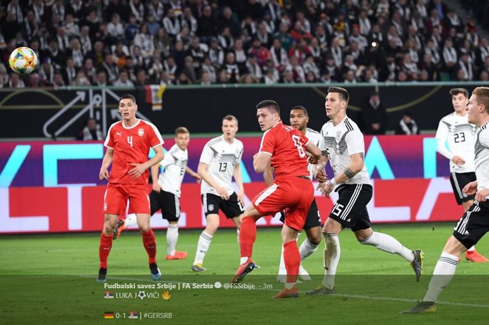Penyerang timnas Serbia, Luka Jovic (jersey merah, tengah), mengarahkan bola dengan sundulan ke arah gawang Jerman pada laga persahabatan, Kamis (21/3/2019), di Volkswagen Arena, Wolsburg.