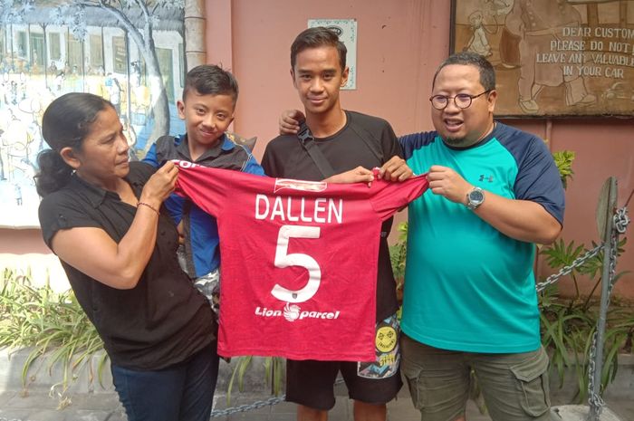 Pemain Bali United, Dallen Doke diapit pemilik MSG, Muly Munial (kanan) dan I Gusti Ketut Arya yang digendong ibunya, Ni Made Sulastri di Desa Kayuputih, Kecamatan Banjar, Kabupaten Buleleng, Jumat (7/6/2019).