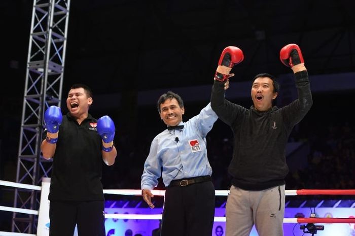Menteri Pemuda dan Olahraga, Imam Nahrawi (kanan), memenangi laga tinju melawan juara dunia WBA, Chris John, pada laga  Kejuaraan Tinju Dunia di GOR Flobamora, Kupang, Nusa Tenggara Timur, Minggu (8/7/2019). 