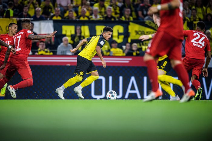 Pemain Dortmund, Jadon Sancho (tengah) mengecoh Thiago Alcantara dan Jerome Boateng dari Bayern Muenchen dalam partai DFL Supercup 2019 antara Borussia Dortmund dan Bayern Muenchen di Signal Iduna Park, 3 Agustus 2019, di Dortmund, Jerman.