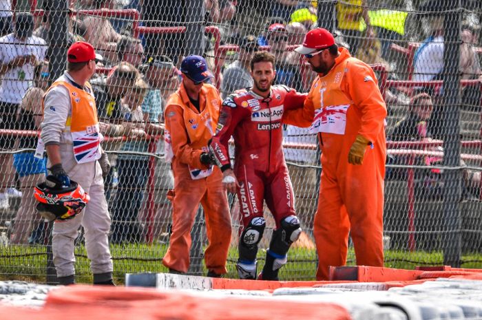 Pembalap Ducati, Andrea Dovizioso, dibantu marshal setelah mengalami kecelakaan pada lap pertama balapan MotoGP Inggris di Sirkuit Silverstone, Minggu (25/8/2019).