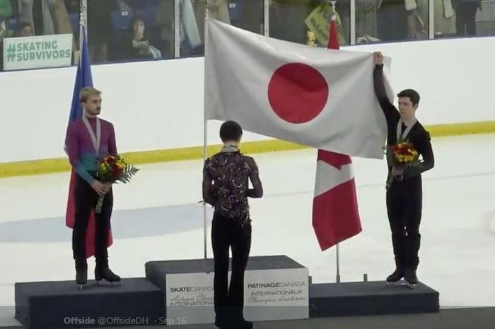 Atlet ice skating, Keegan Messing, membantu membentangkan bendera Jepang untuk pesaingnya yang menjadi juara, Yuzuru Hanyu, ketika melakukan perlombaan Autumn Classic di Ontario, Kanada.