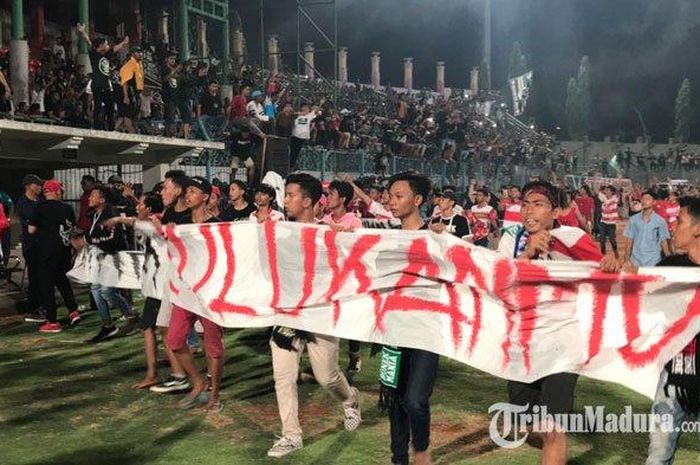 Suporter Madura United masuk ke dalam lapangan dan meminta sang pelatih, Rasiman, mundur dari kursi pelatih setelah kalah 2-3 dari Persebaya, Senin (2/12/2019). 